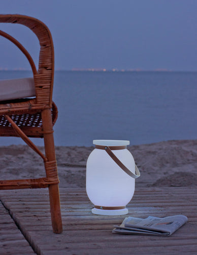 Candela draagbare lamp op het strand bij schemer 