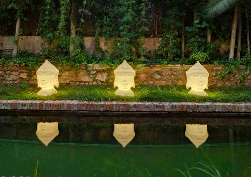 Drie Boeddha buitenlampen buiten in de avond bij de vijver